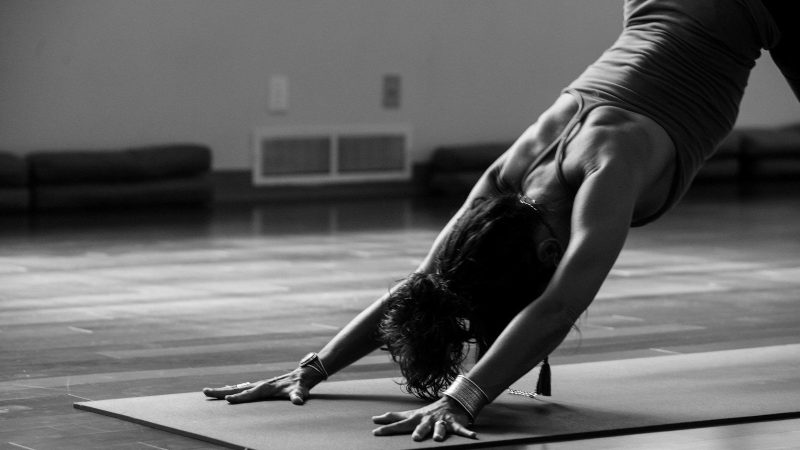 Frau im schwarzen Top macht Yoga auf einer Yoga Matte